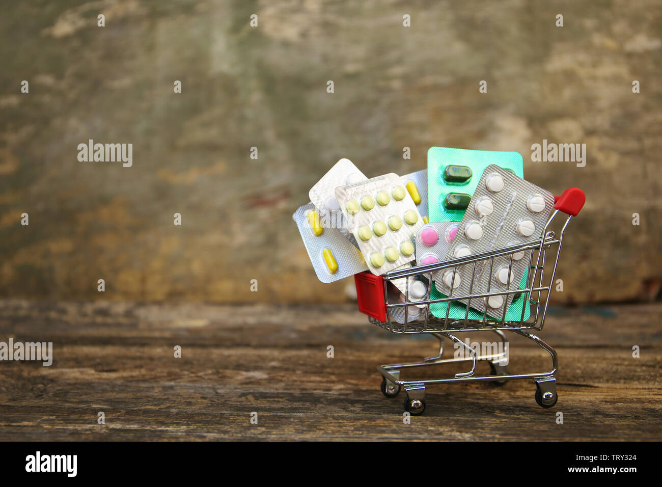 Shopping cart with pills on old wood background. Stock Photo