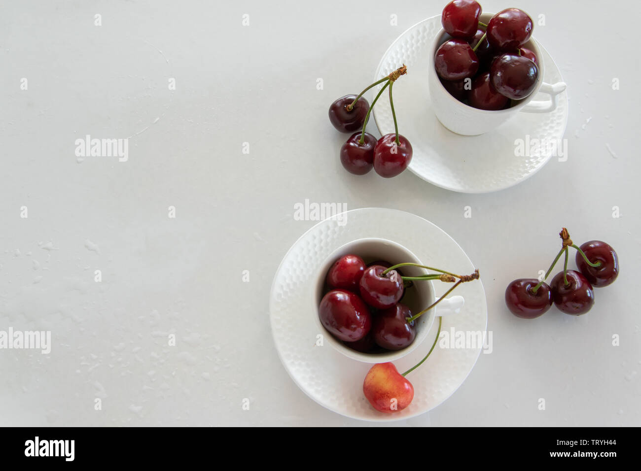 Cherries season. Top view of raw cherries in white cups and bowls Stock