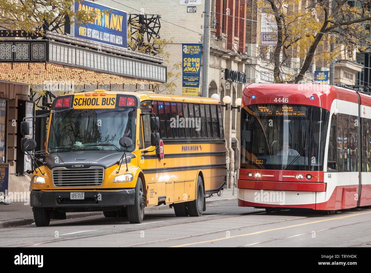 TORONTO, CANADA - NOVEMBER 14, 2018: Toronto Streetcar passing next to a Yellow American School bus, Downtown Toronto, Ontario. It is one of symbols o Stock Photo