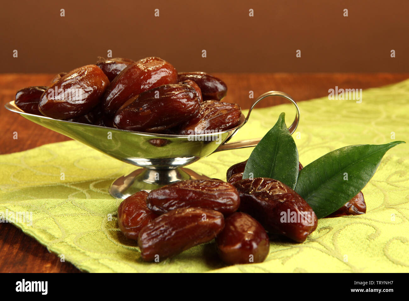 Dried dates in metal dish on table on brown background Stock Photo Alamy