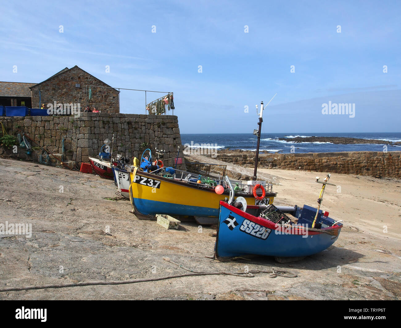 Very colourful fishing boats hauled up on to the quay at Sennen Cove ...