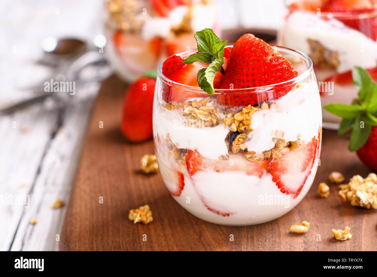 Healthy breakfast of strawberry parfaits made with fresh fruit, yogurt and granola over a rustic white table. Selective focus. Stock Photo