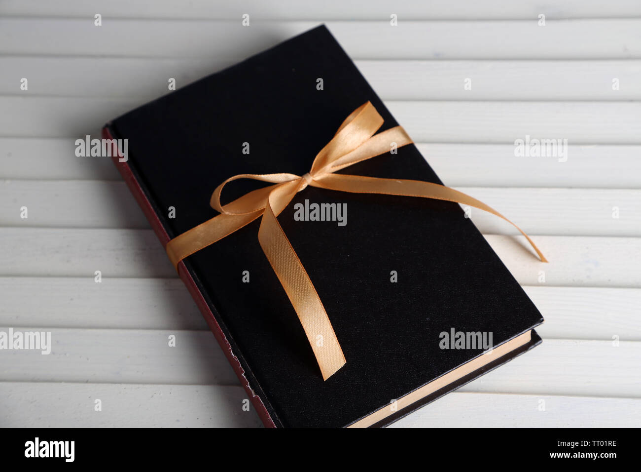 Book wrapped with color ribbon, on wooden background Stock Photo - Alamy
