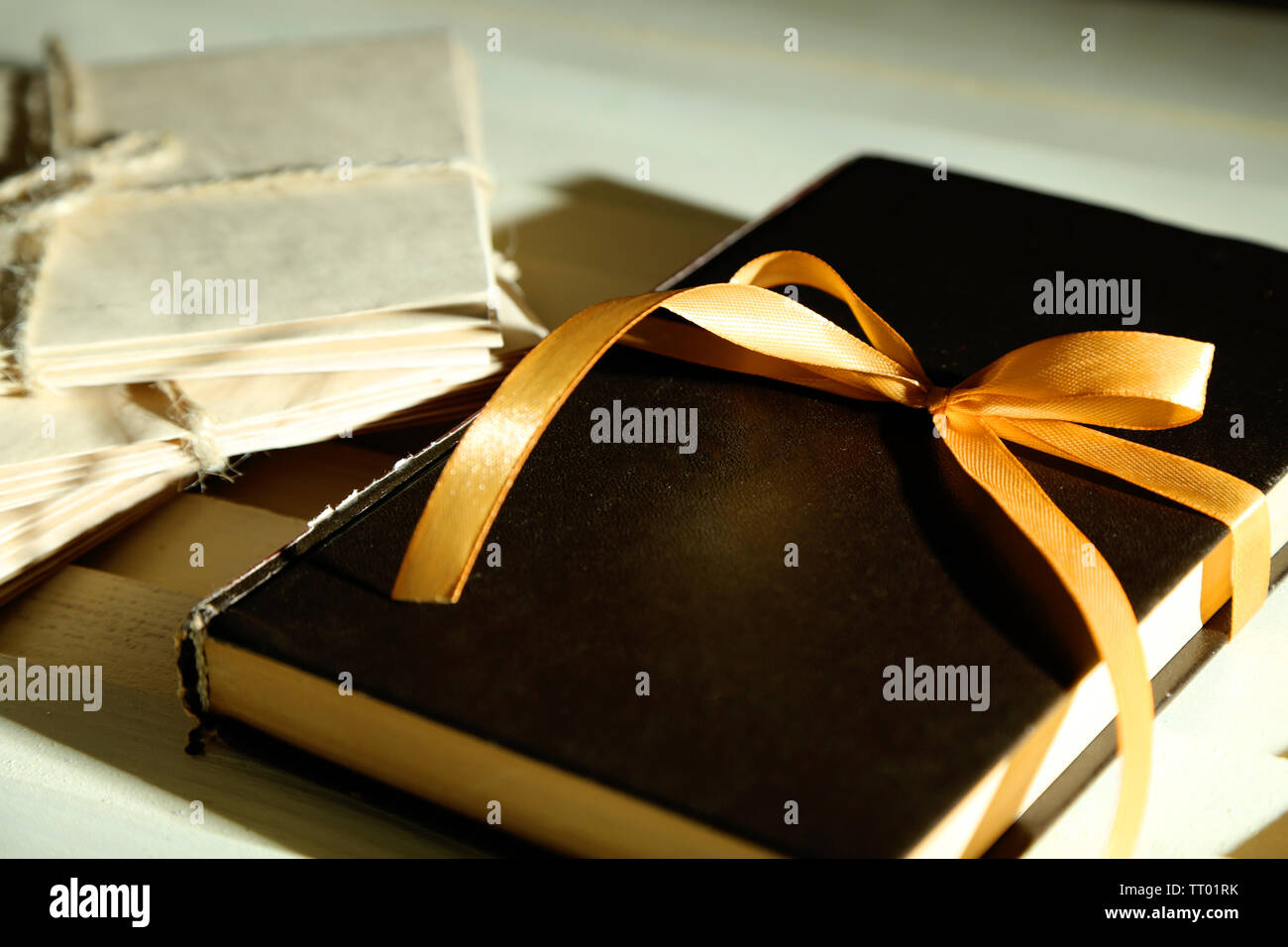 Book wrapped with color ribbon, on wooden background Stock Photo - Alamy