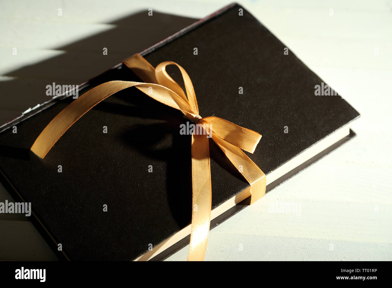 Book wrapped with color ribbon, on wooden background Stock Photo - Alamy