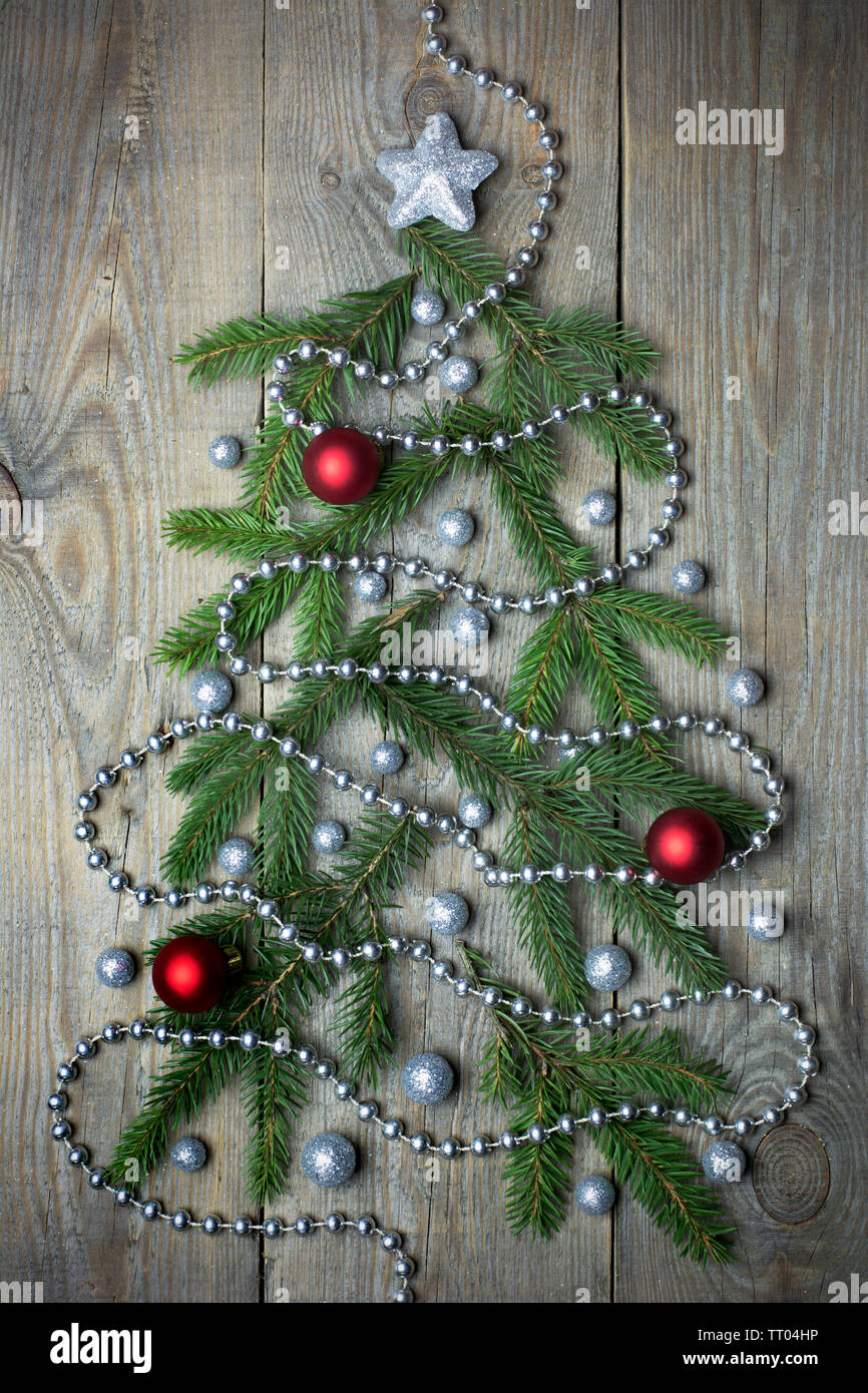 Christmas tree concept with green fir tree branches, glitter globules, red baubles and bead chain on wooden background Stock Photo