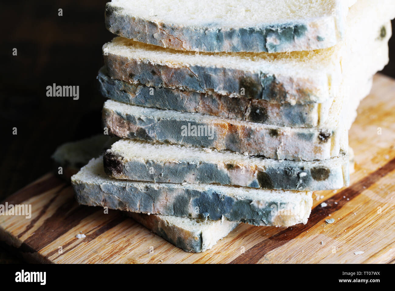 Mouldy bread on cutting board, on wooden background Stock Photo