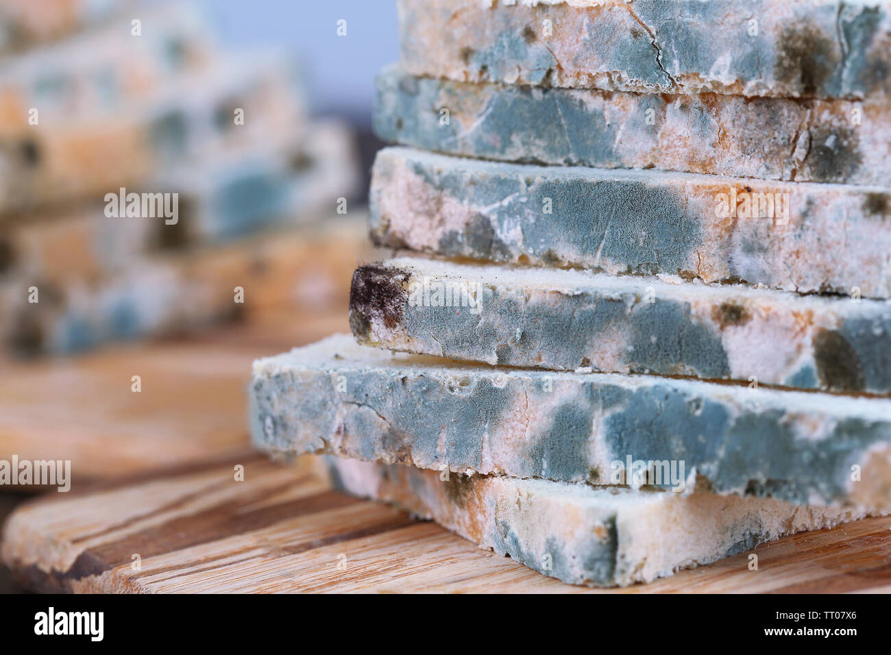 Mouldy bread on cutting board, on wooden background Stock Photo