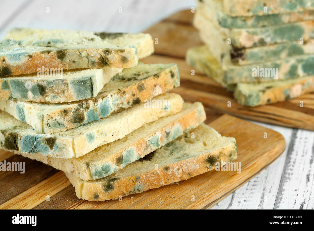 Mouldy bread on cutting board, on wooden background Stock Photo