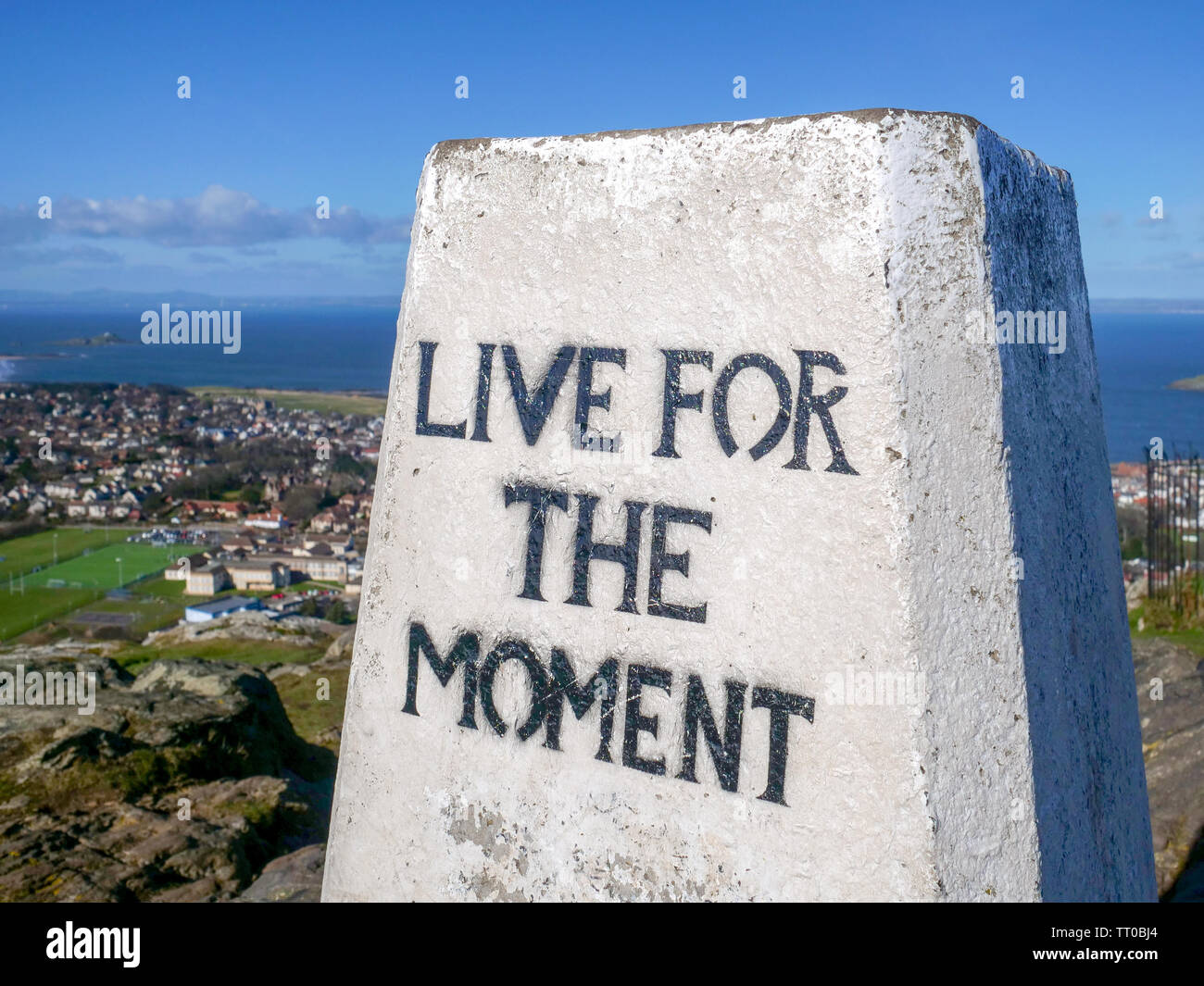 'Live for the moment' message on the triangulation pillar on the top of North Berwick Law, East Lothian, Scotland, UK. Stock Photo