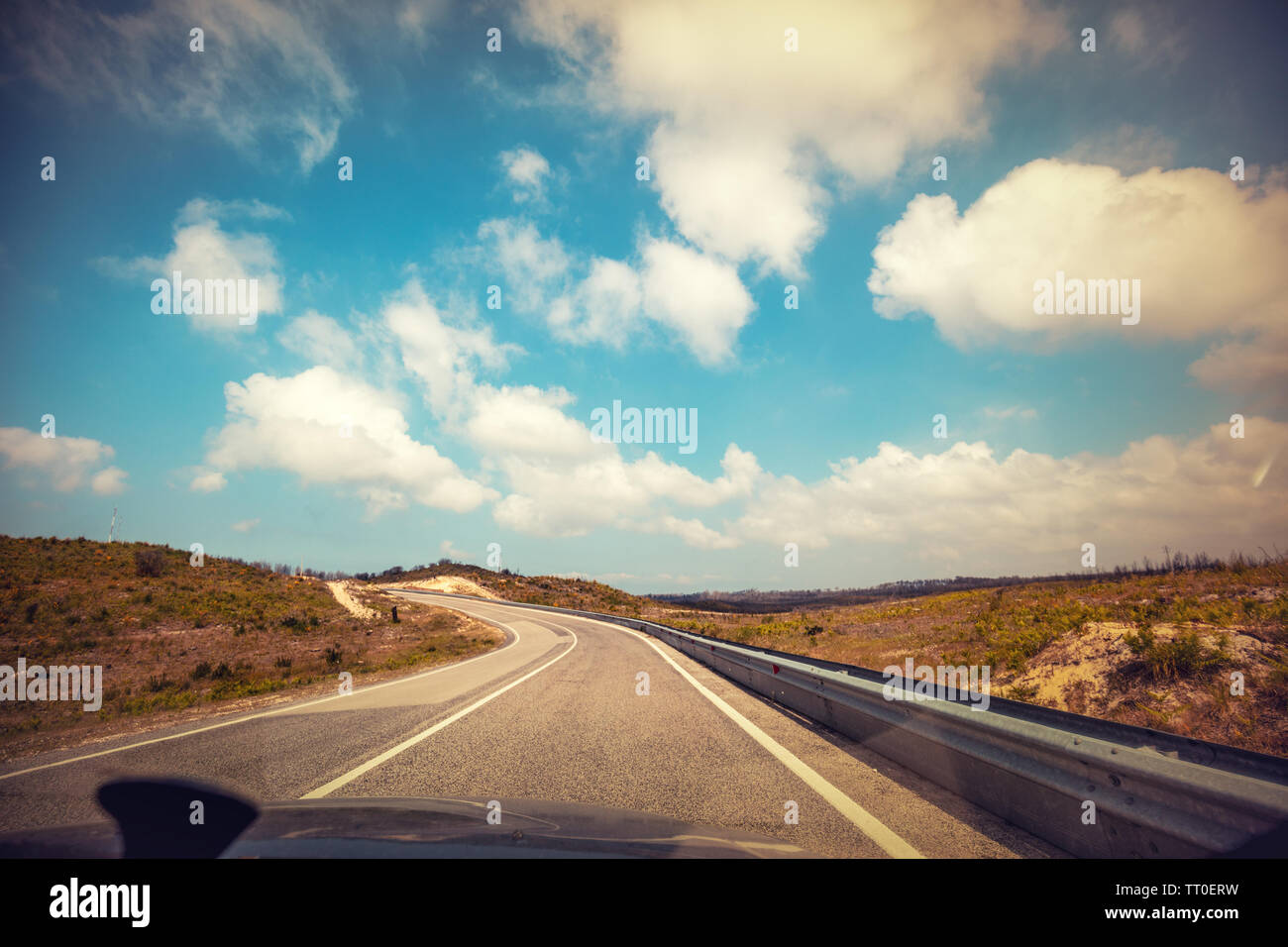 Driving a car on a winding mountain road in Portugal on a sunny day with a cloudy sky Stock Photo