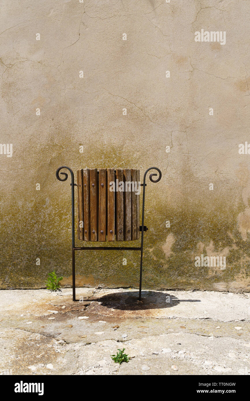 Solitary trashcan can with ornate frame and two small sprouting plants stand out from a dreary environment, background with copy space - vertical orie Stock Photo