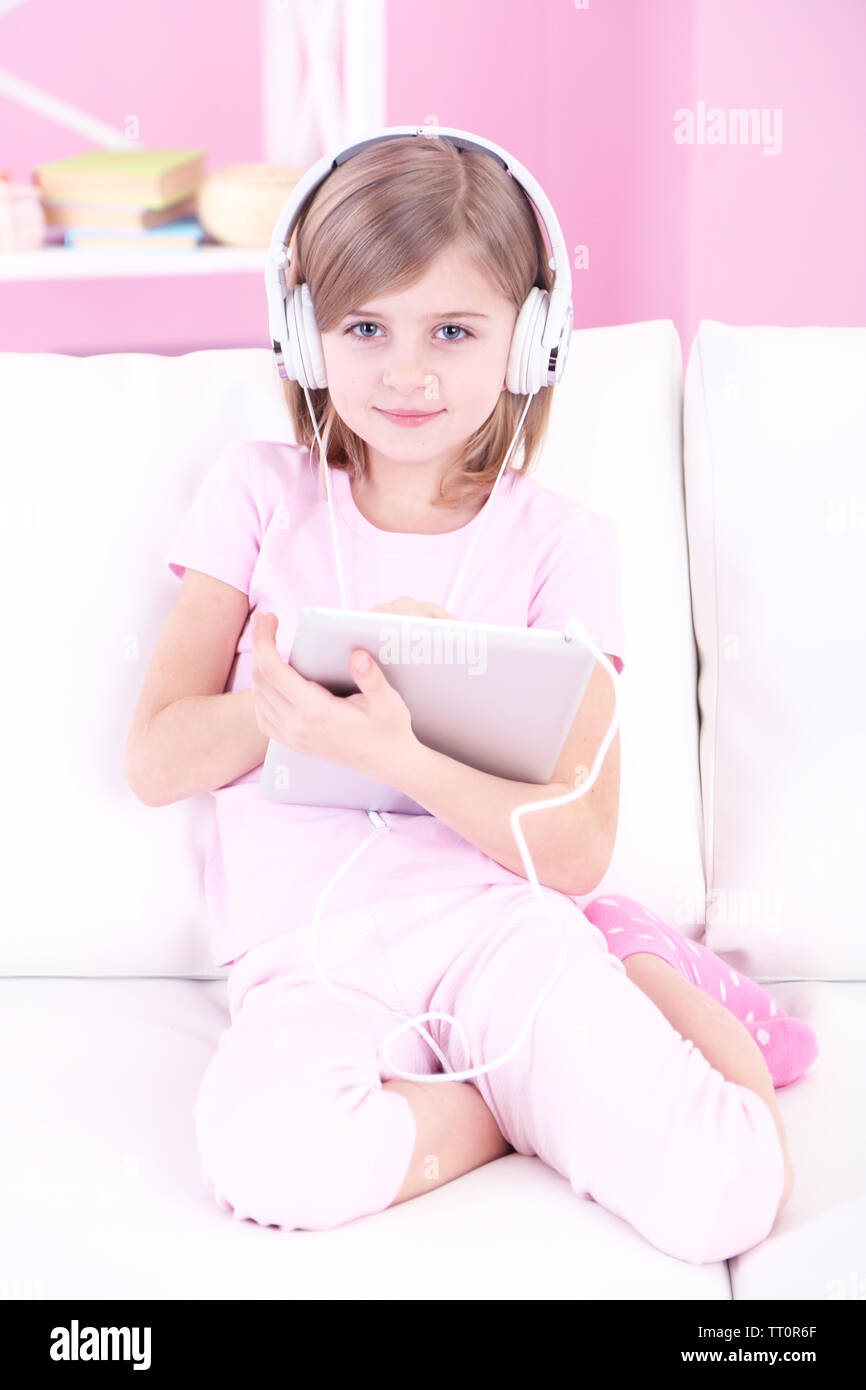 Little girl sitting on sofa and listening music in room Stock Photo - Alamy