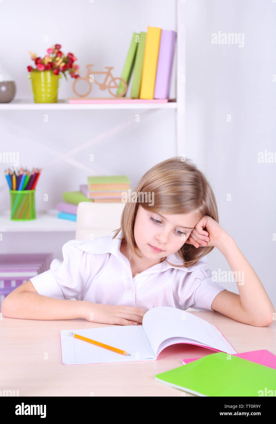 Little girl sitting at desk in room Stock Photo - Alamy