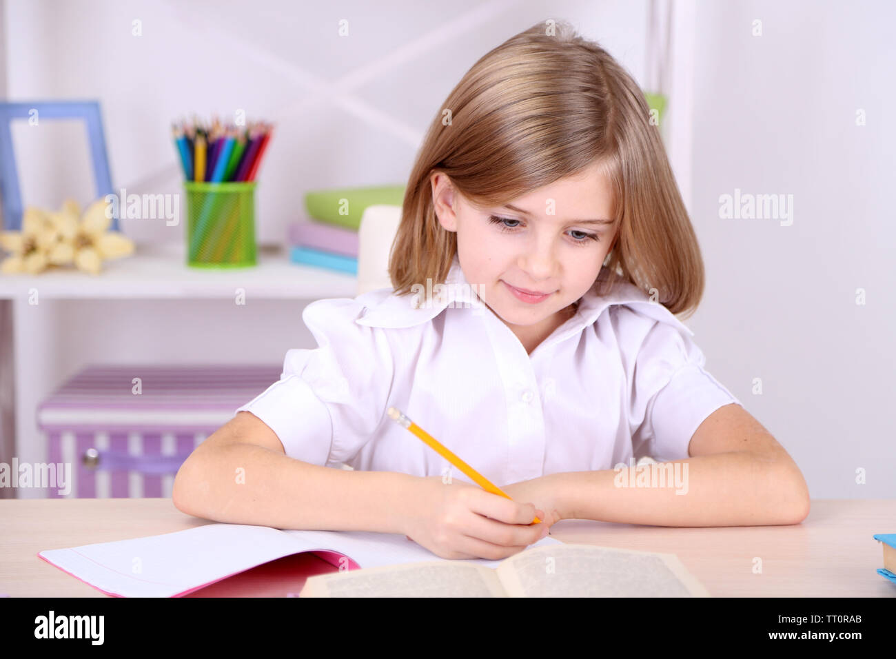 Little girl sitting at desk in room Stock Photo - Alamy