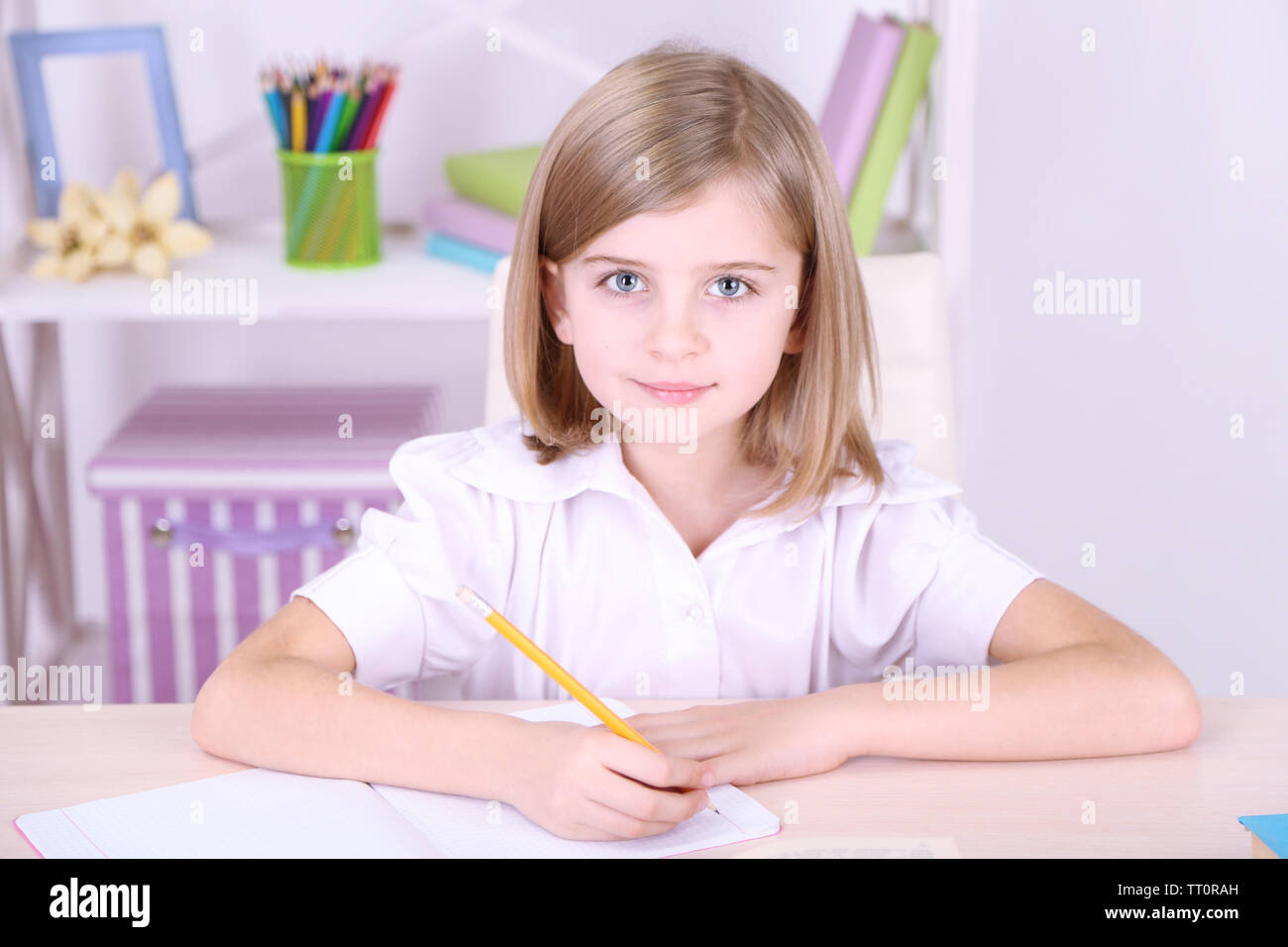 Little girl sitting at desk in room Stock Photo - Alamy