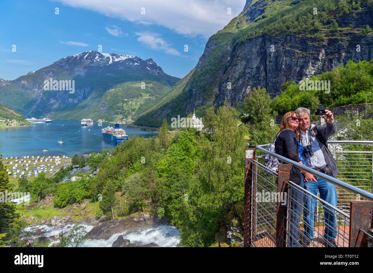 Middle aged couple taking a selfie at the Storfossen Waterfall overlooking the harbour at Geiranger, Møre og Romsdal, Sunnmøre, Norway Stock Photo