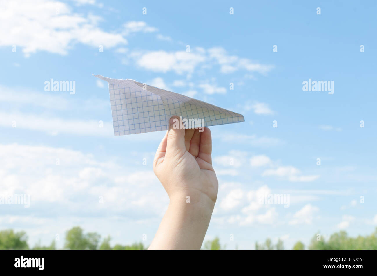 Hand of little boy runs paper airplane in the sky.On bright Sunny day ...