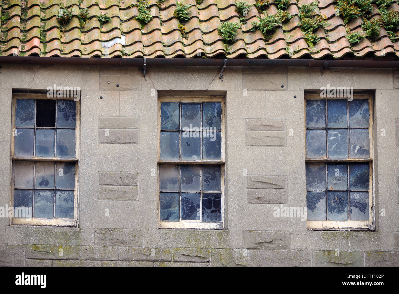 Dirty sash windows above a shop on Dunbar high Street, East Lothian, Scotland Stock Photo