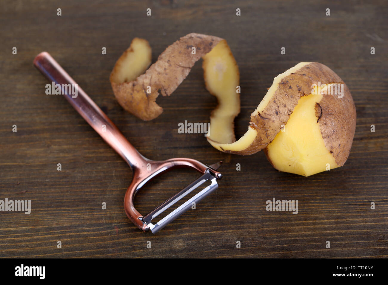 https://c8.alamy.com/comp/TT10NY/peeler-and-fresh-potato-on-wooden-background-TT10NY.jpg