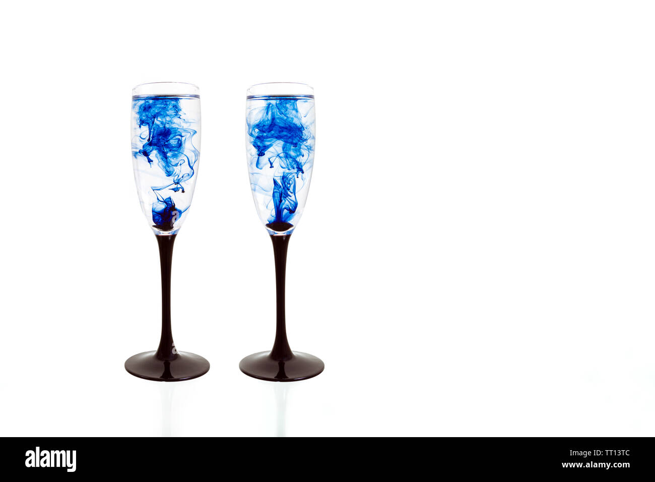 Two wine glasses on white background with blue color paints inside