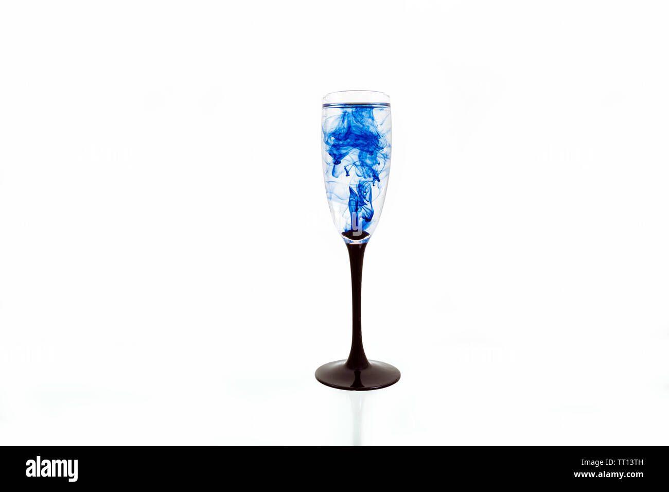 Wine glass on white background with blue color paints inside. Fougere