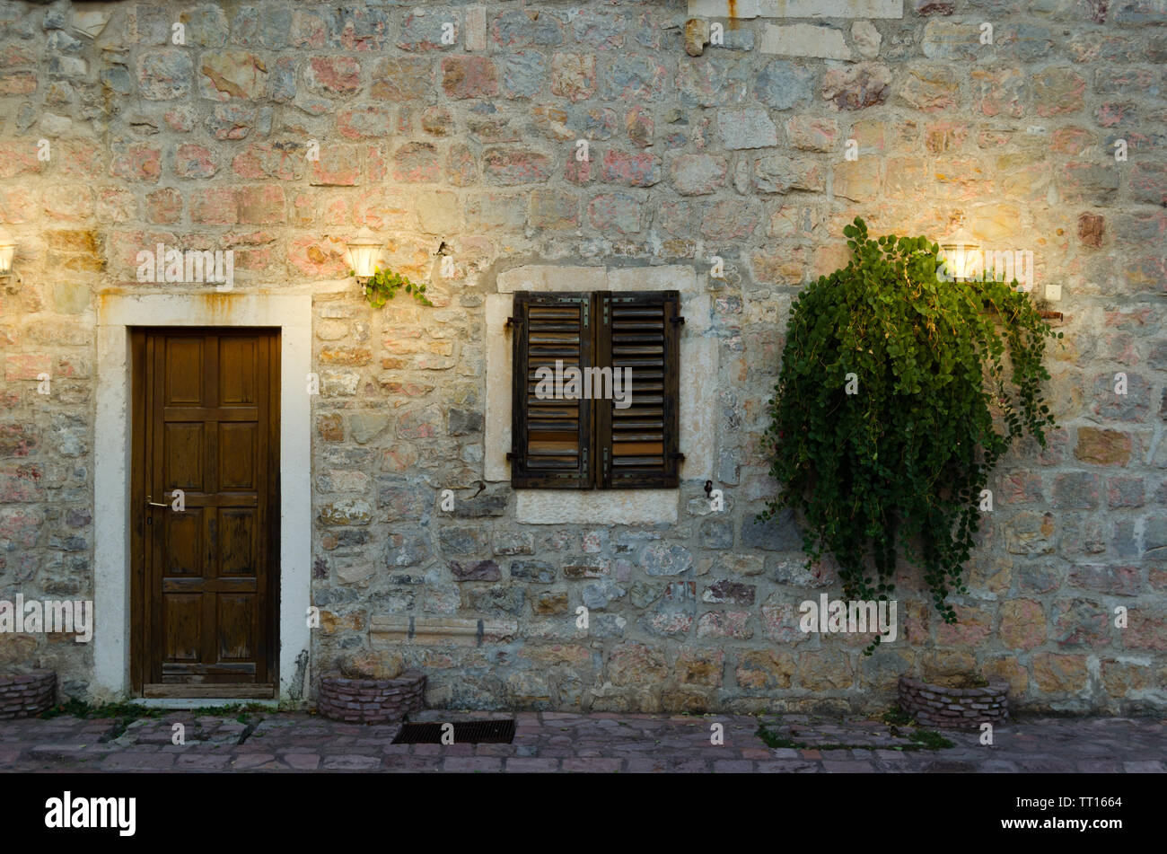 Facade of old house with a wooden door and a window, lit by two ...
