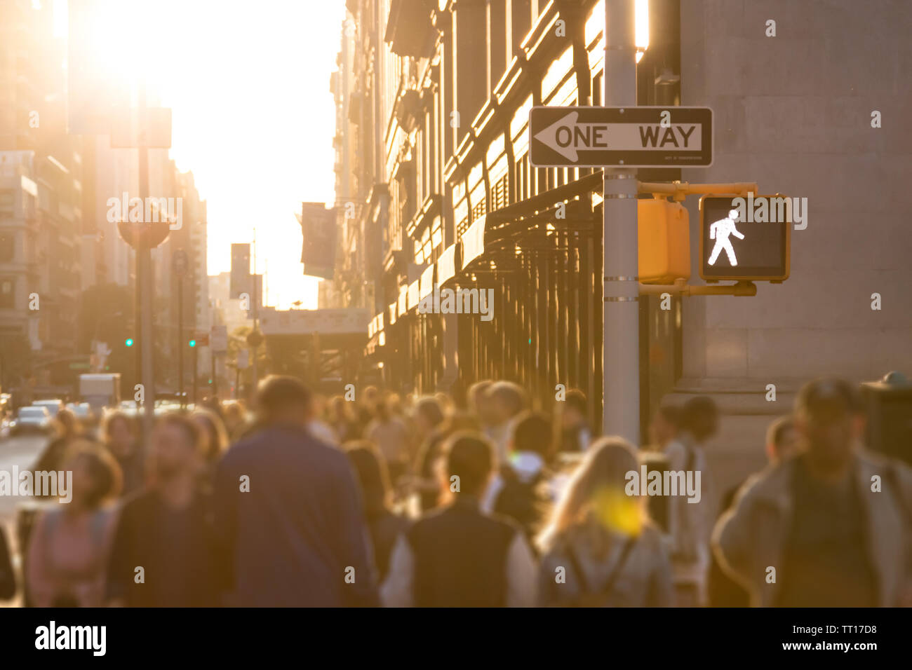 Sunlight shines on the busy crowds of anonymous people walking down the ...