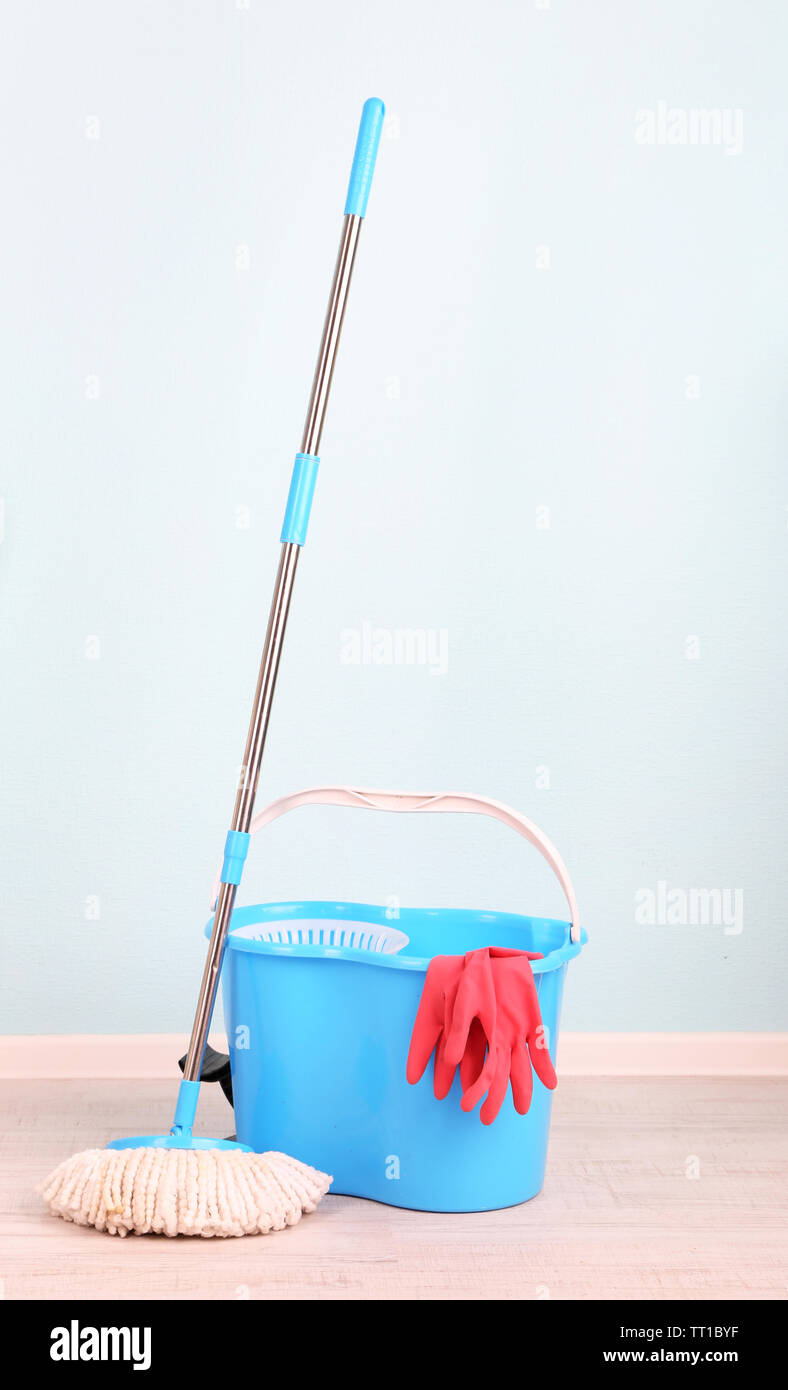 Floor mop and bucket for washing in room on blue wall background Stock ...