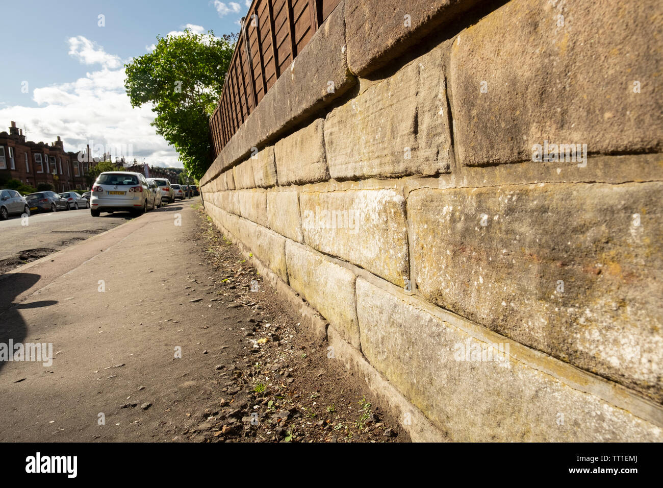 Stone wall catching sunshine, and pavement, in the Victorian suburb of