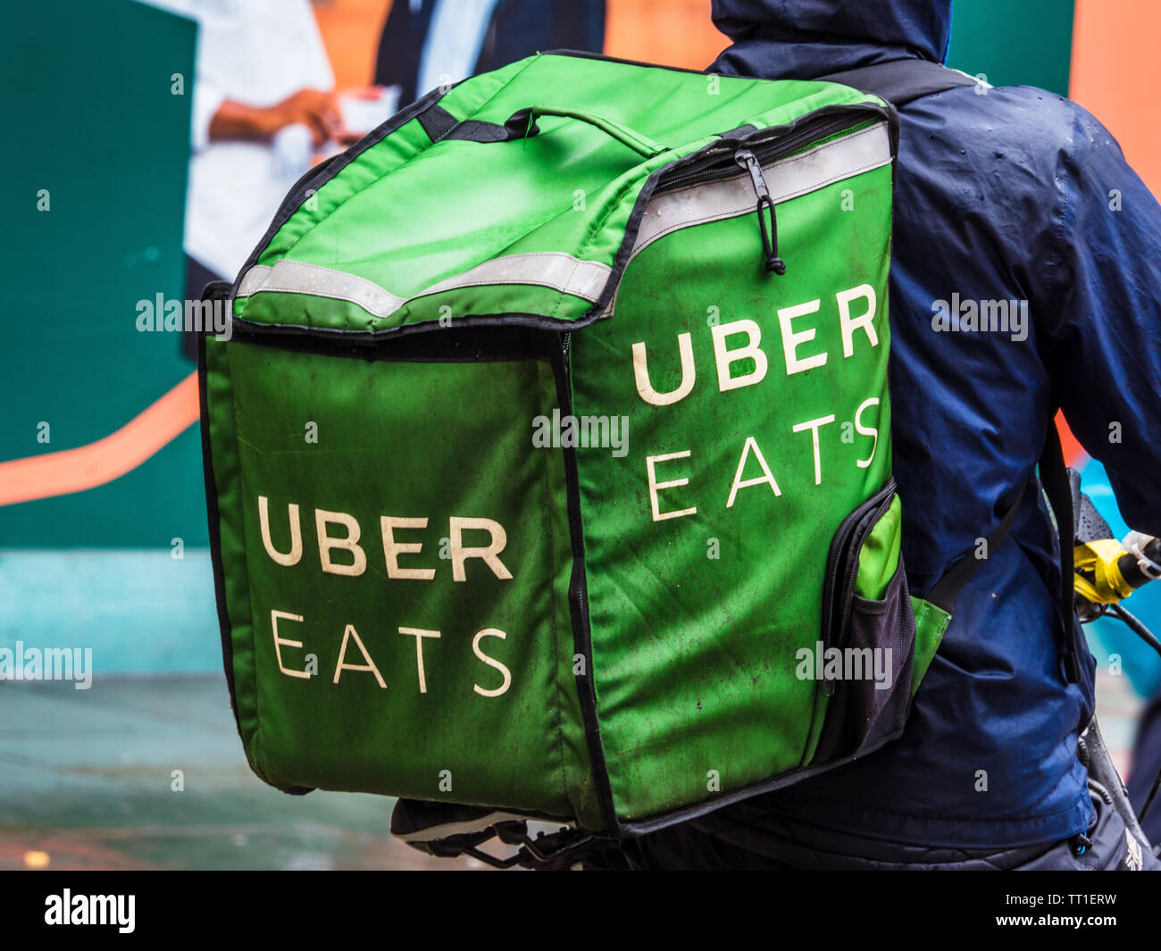 Uber Eats Courier in heavy rain in London - an Uber Eats Food Delivery Courier getting drenched in a heavy downpour Stock Photo