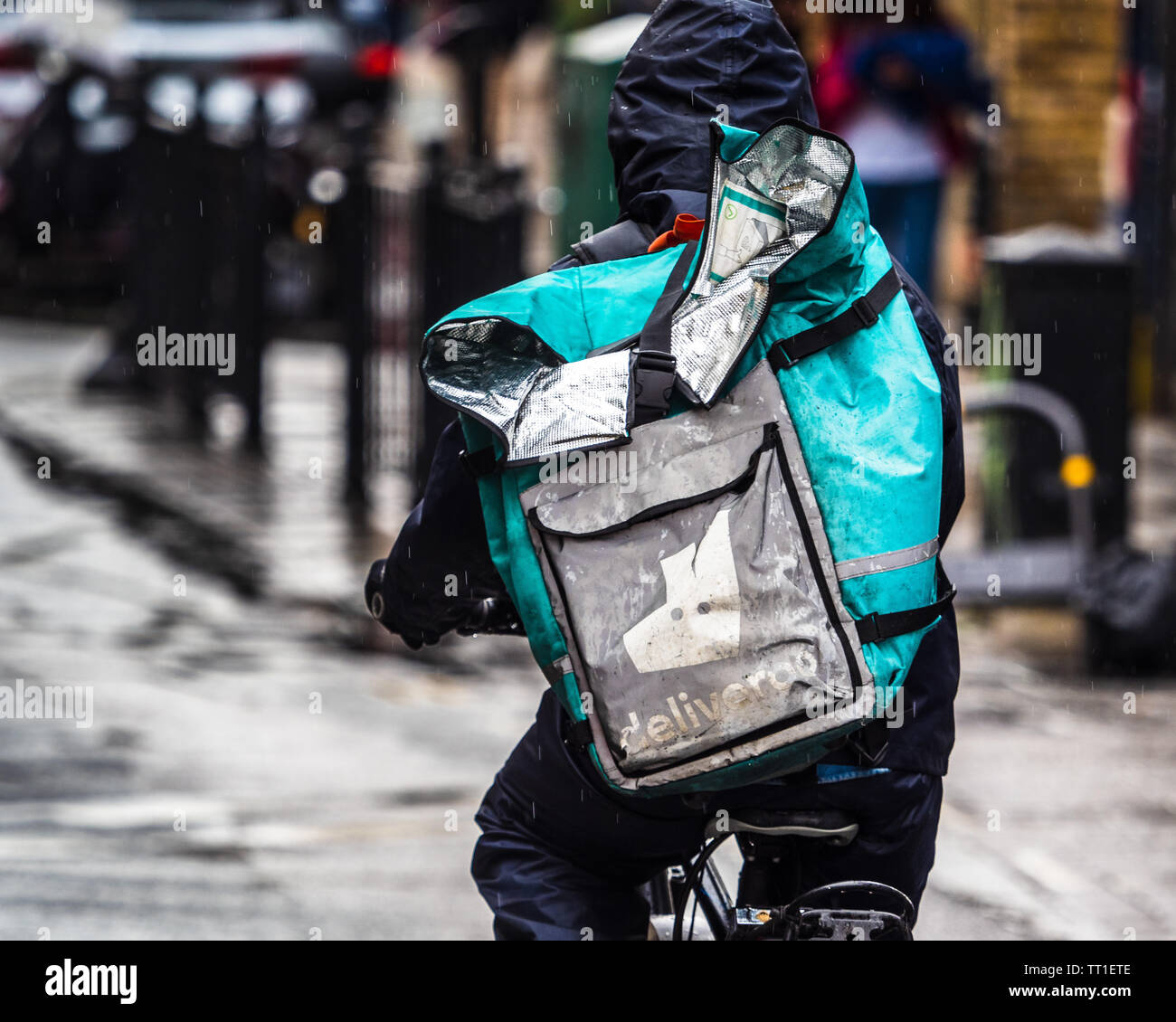 Deliveroo Courier in heavy rain in London - a Deliveroo Food Delivery Courier getting drenched in a heavy downpour Stock Photo