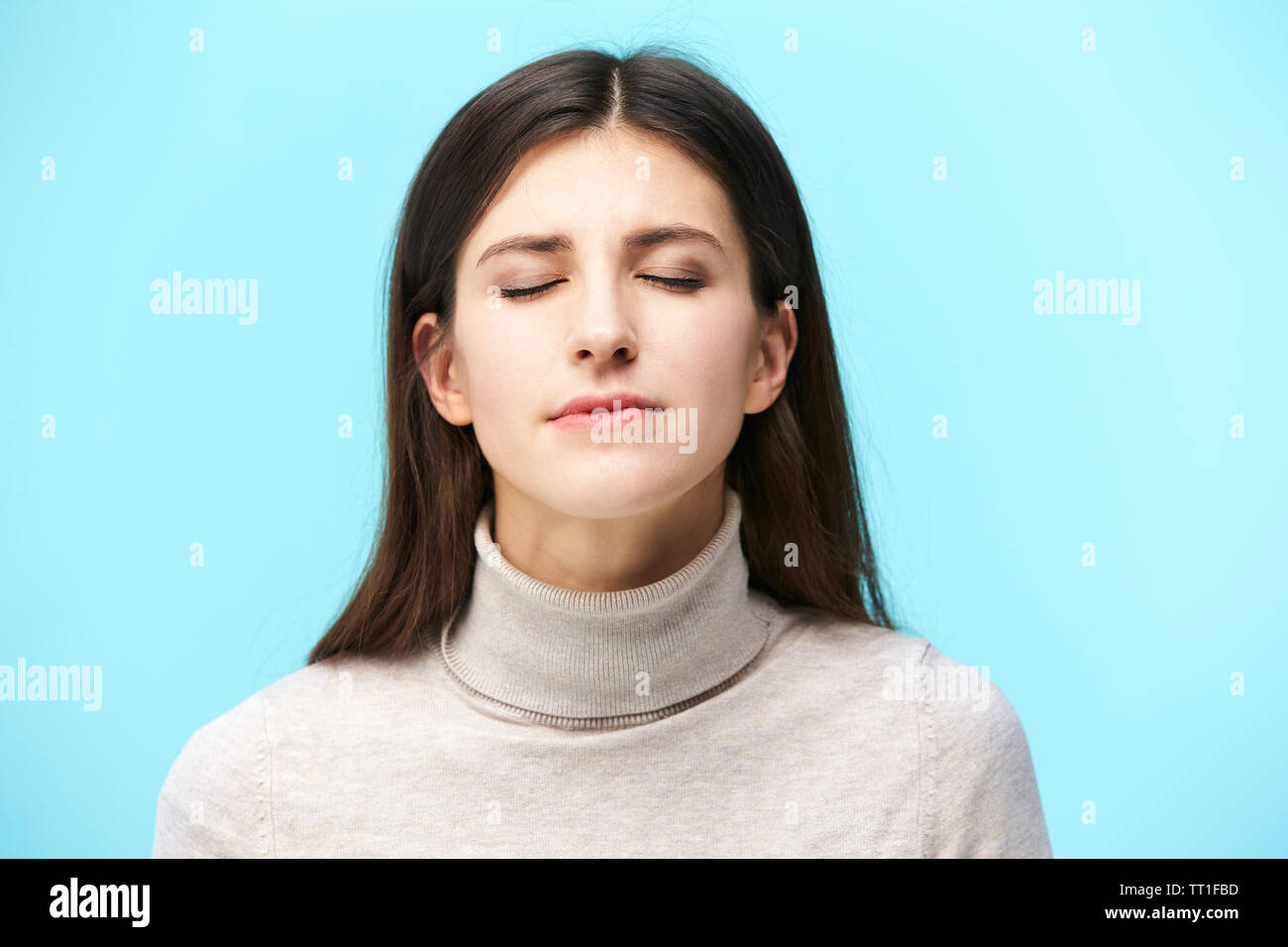 portrait of a young caucasian woman, eyes closed, isolated on blue background Stock Photo