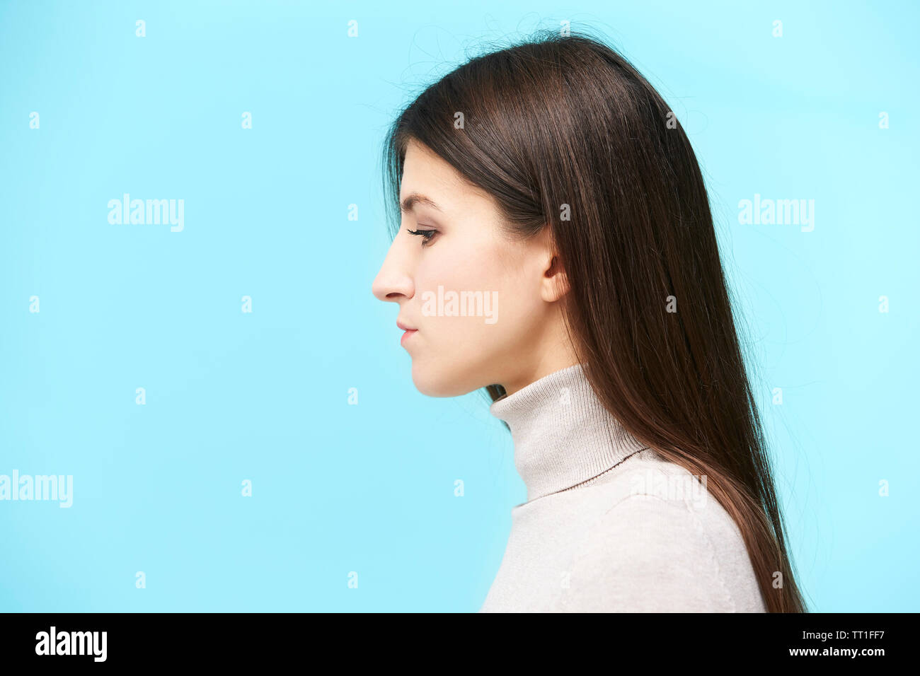 portrait of a young caucasian woman, looking down, side view, isolated on blue background Stock Photo