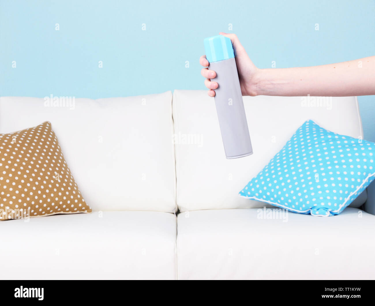 Sprayed air freshener in hand on home interior background Stock Photo