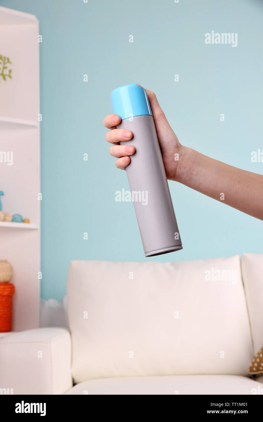Sprayed air freshener in hand on home interior background Stock Photo