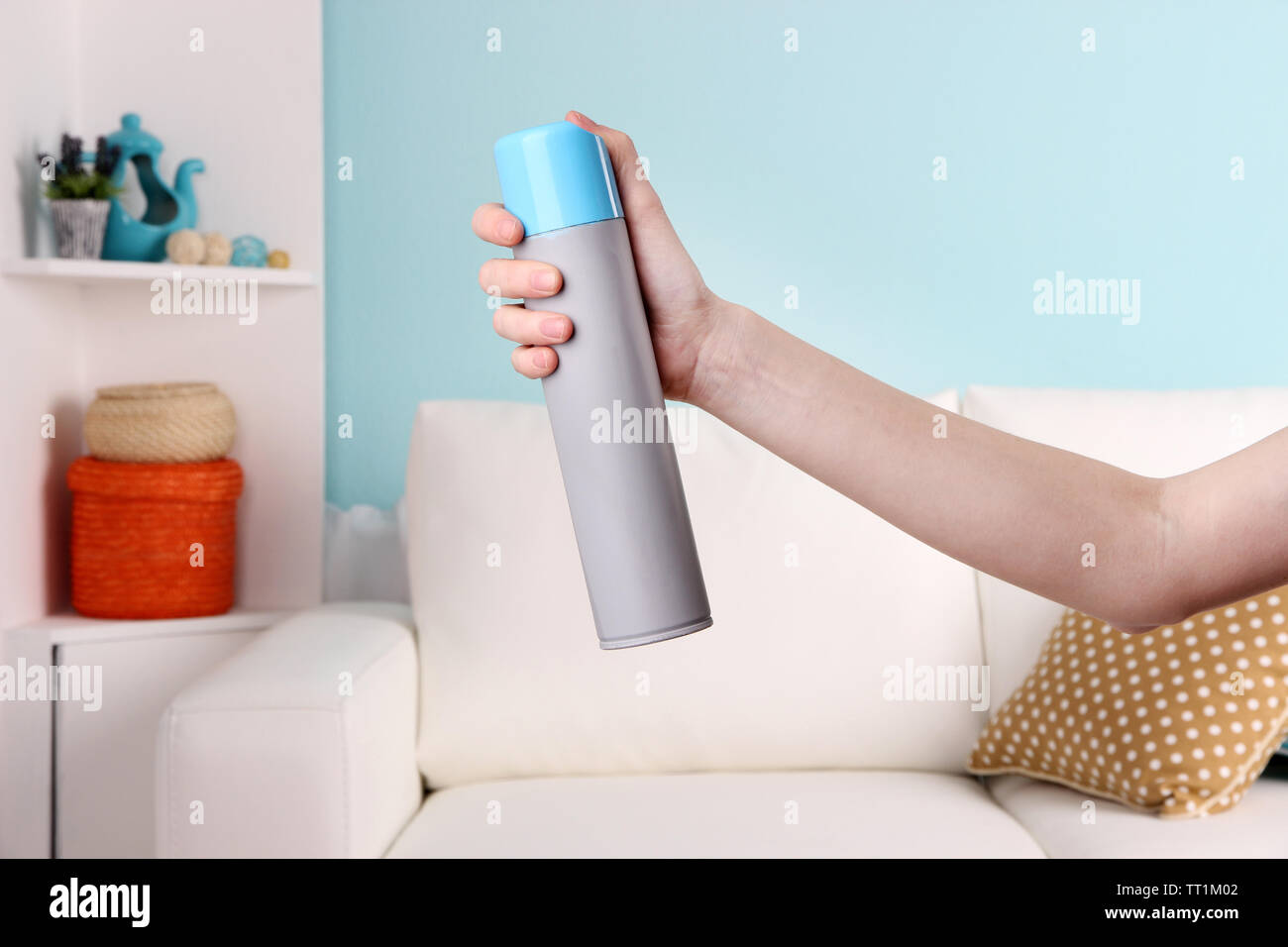 Sprayed air freshener in hand on home interior background Stock Photo