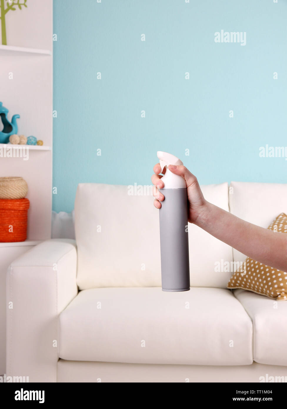 Sprayed air freshener in hand on home interior background Stock Photo