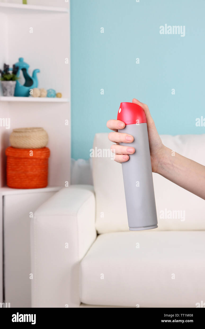 Sprayed air freshener in hand on home interior background Stock Photo