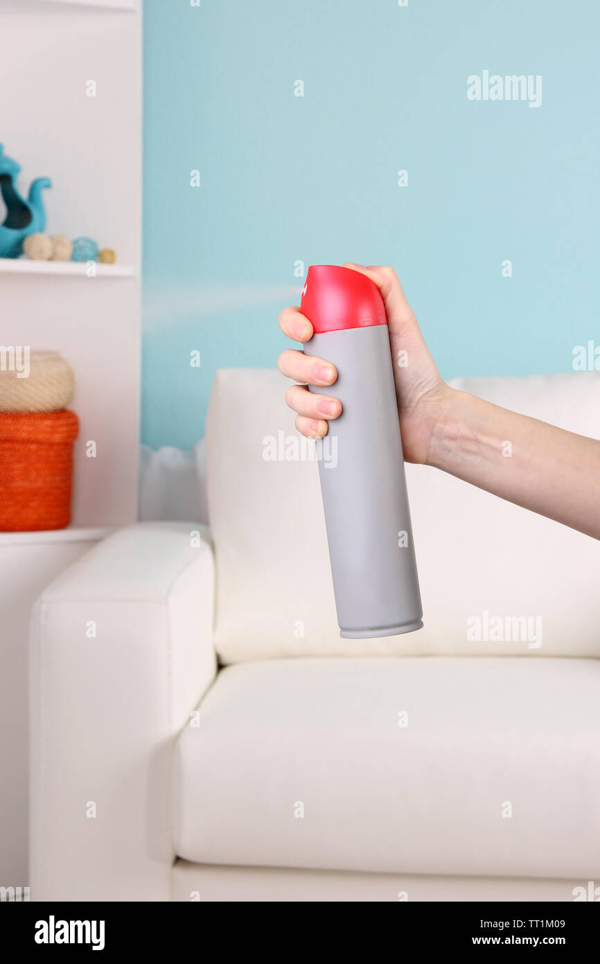Sprayed air freshener in hand on home interior background Stock Photo