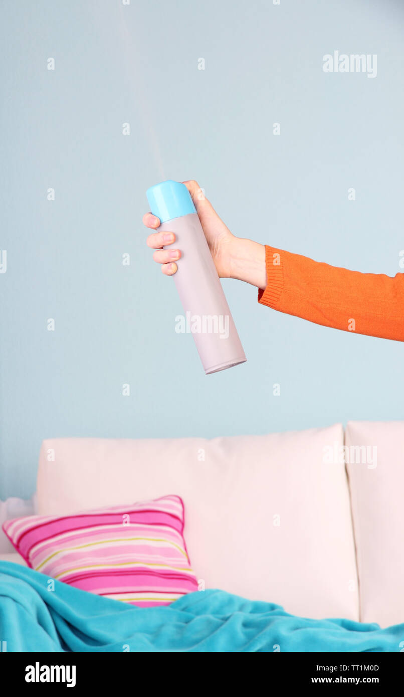 Sprayed air freshener in hand on home interior background Stock Photo