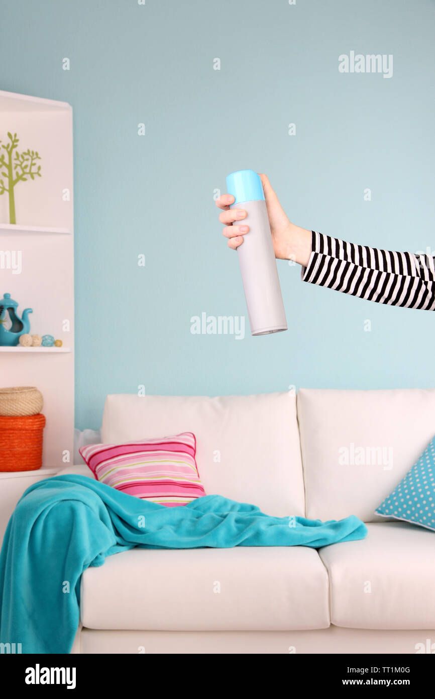 Sprayed air freshener in hand on home interior background Stock Photo