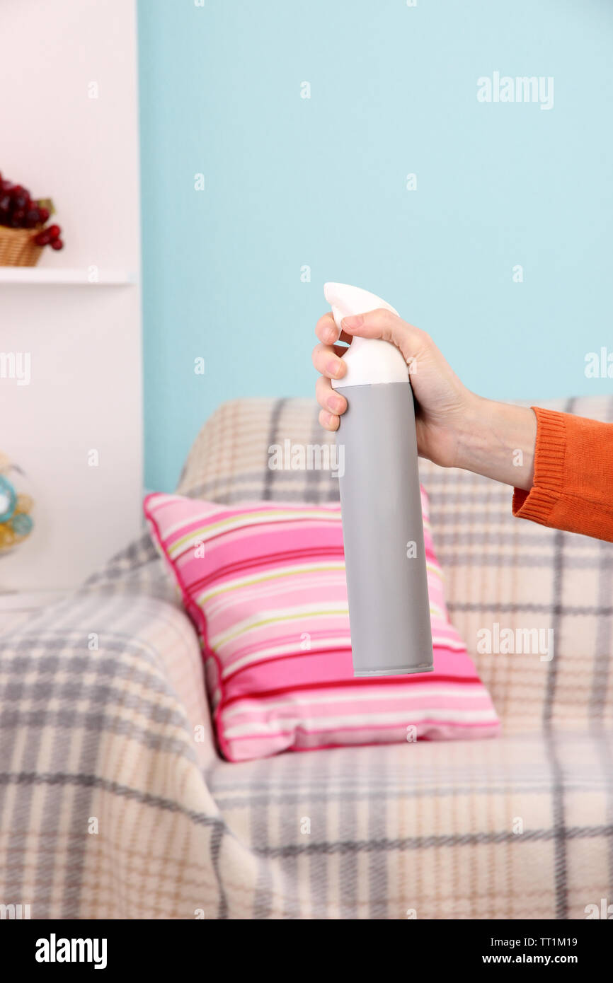 Sprayed air freshener in hand on home interior background Stock Photo