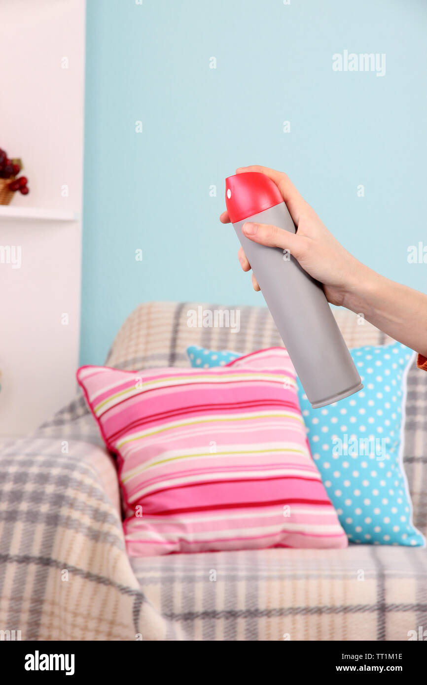 Sprayed air freshener in hand on home interior background Stock Photo