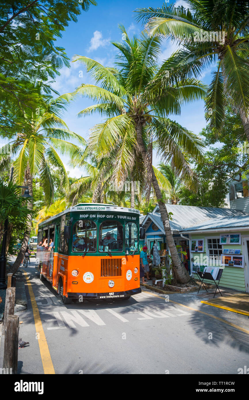 KEY WEST, FLORIDA, USA - SEPTEMBER, 2018: Tourists ride a hop-on hop-off sightseeing bus past the traditional colorful shacks of Old Town. Stock Photo