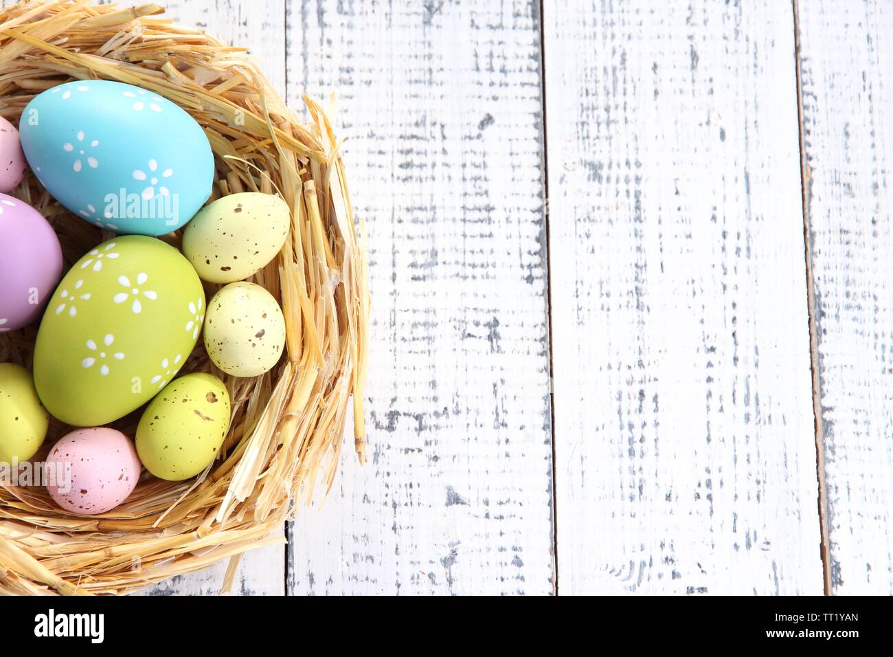 Easter eggs in nest on color wooden background Stock Photo - Alamy