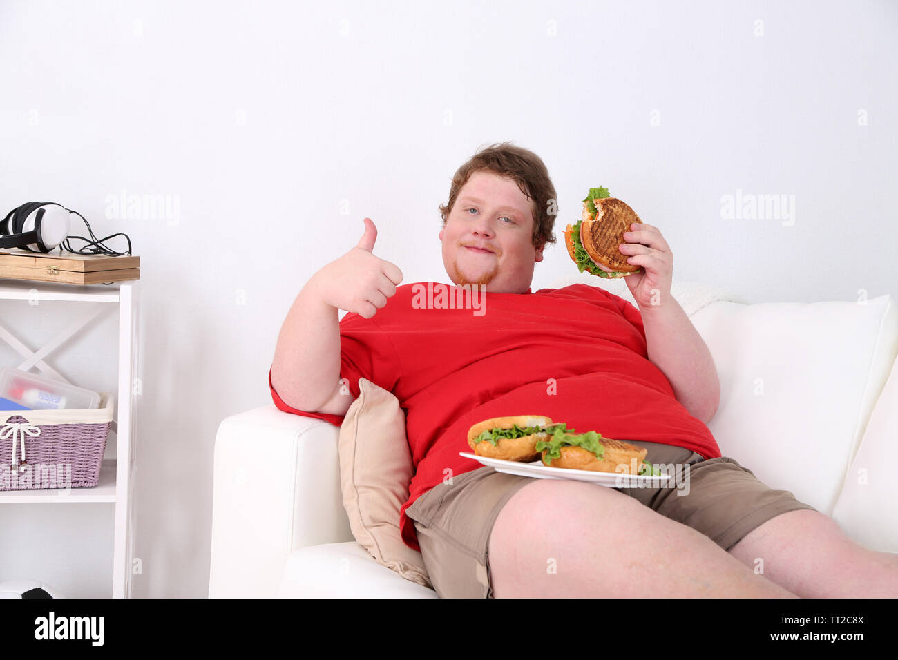 Fat Man Eating Tasty Sandwich On Home Interior Background Stock