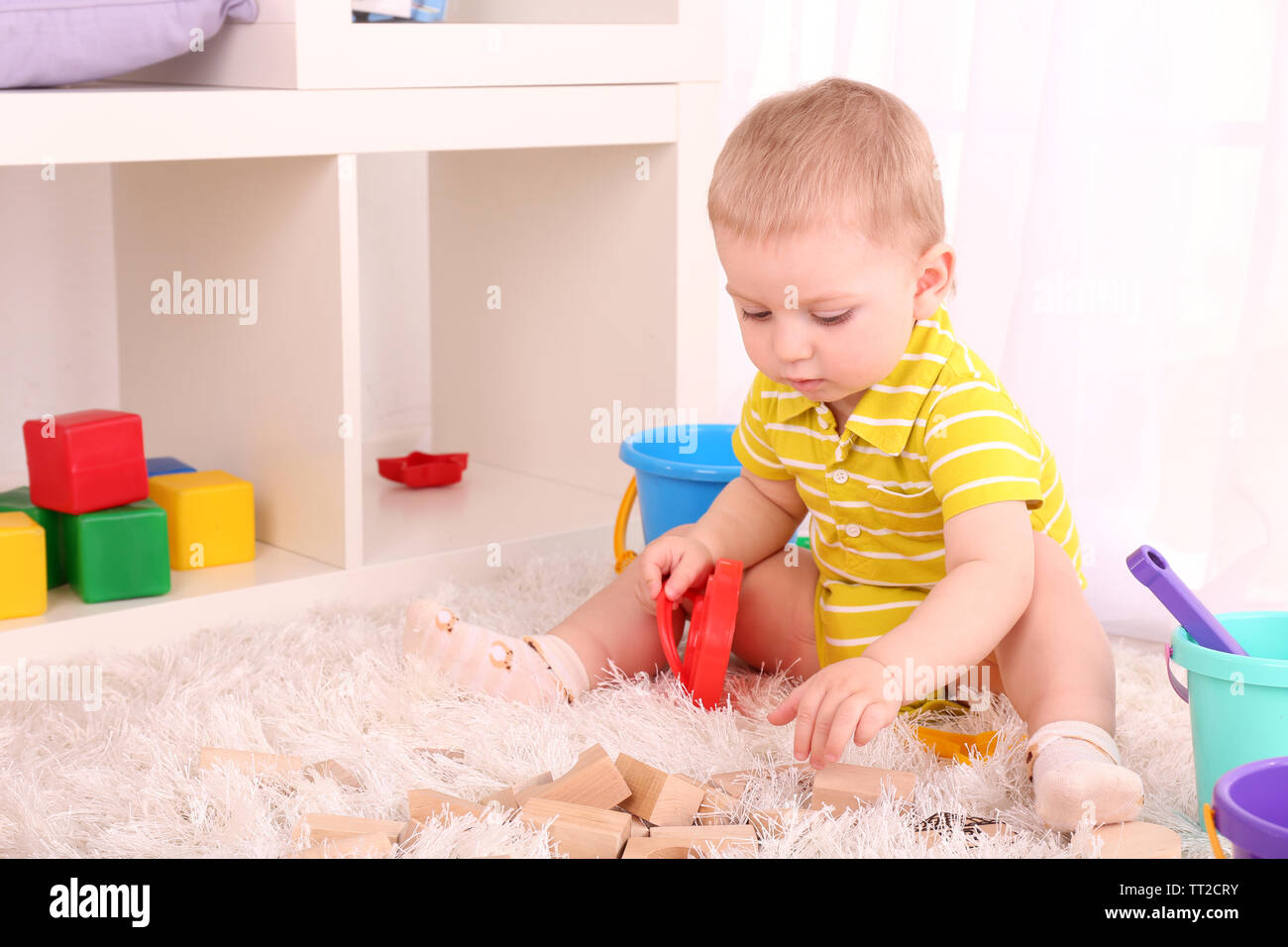 Cute little boy with wooden toy blocks in room Stock Photo - Alamy