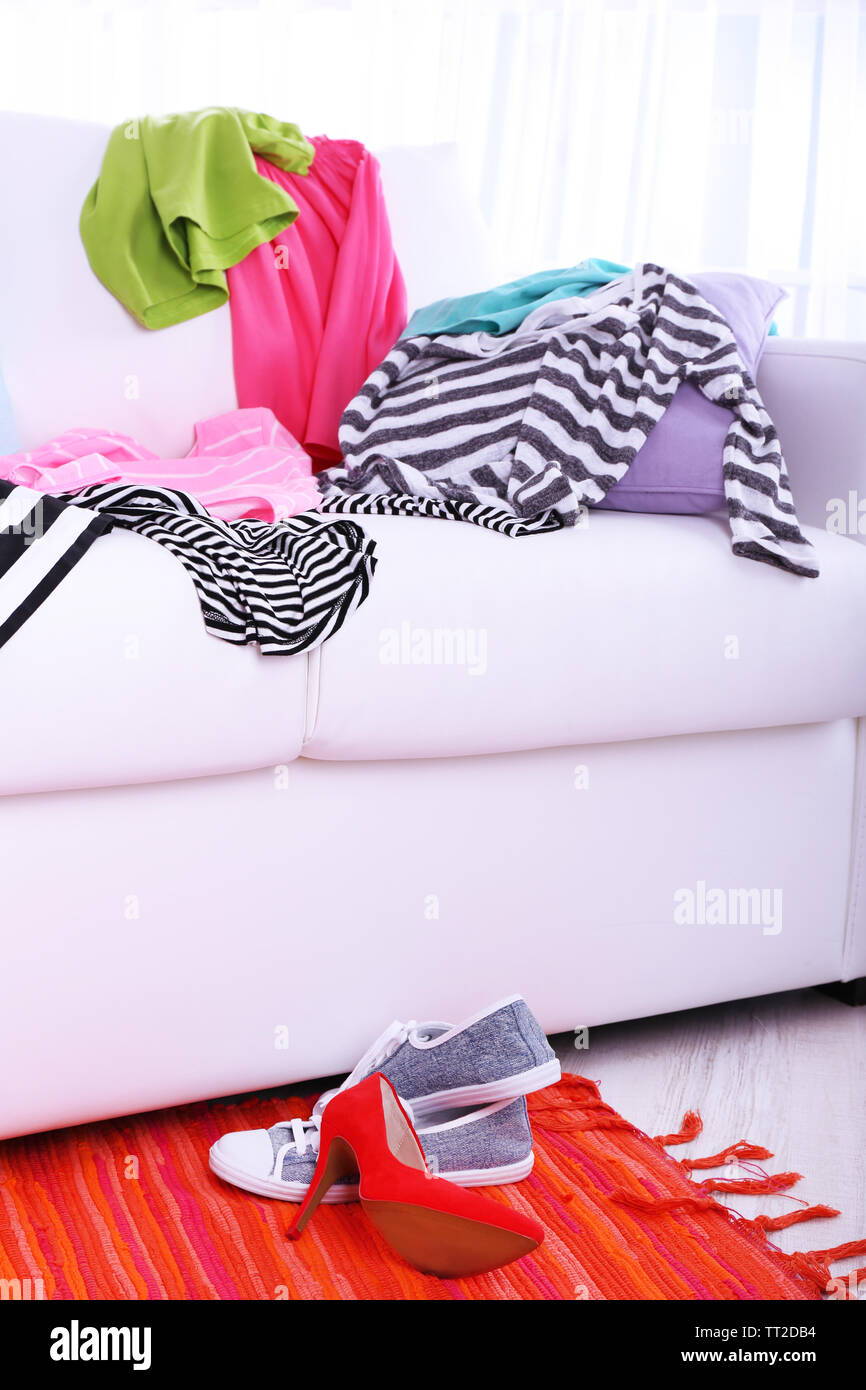 Messy colorful clothing on sofa on light background Stock Photo - Alamy