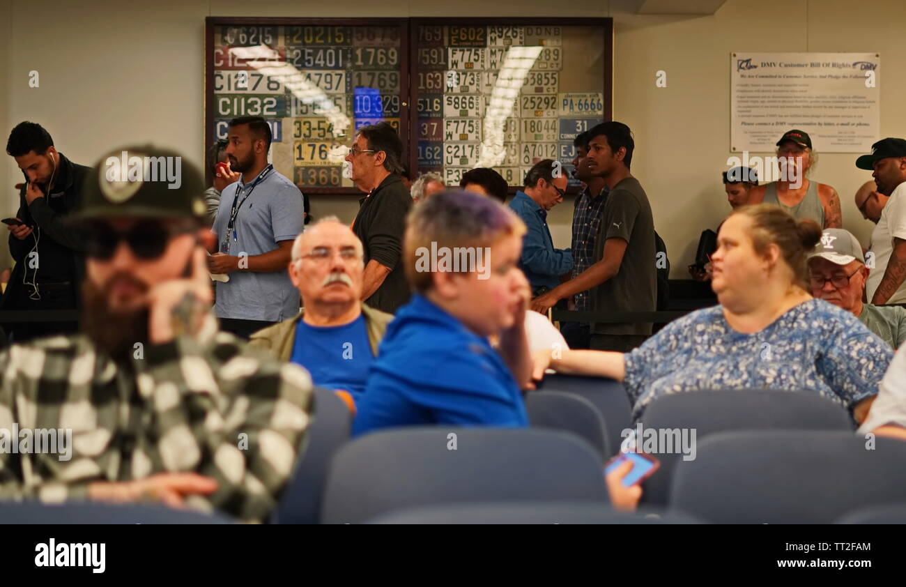 Wethersfield, CT / USA - June 11, 2019: Snapshot of a bored crowd of people in the waiting area (focus on those standing in line) Stock Photo